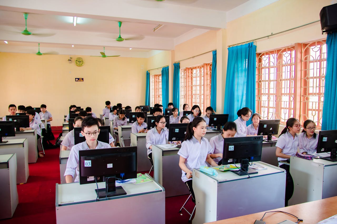services-05 Asian students in uniform learning in a computer lab, focused on their tasks.